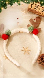 Detailed close-up of Christmas reindeer antler headband with festive plush balls and pine cones