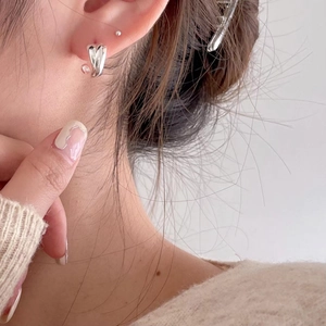 Detail of silver heart earrings on model with minimalist design and metallic shine