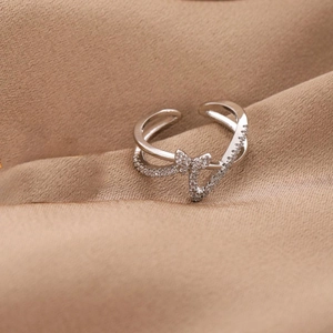 Close-up of silver butterfly ring with small clear diamonds on a beige fabric