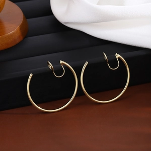Close-up of golden round clip-on earrings for non-pierced ears on a black display stand