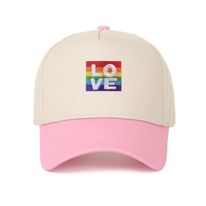 Dettaglio del ricamo LOVE arcobaleno su un cappellino bicolore beige e rosa
