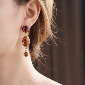Orecchini lunghi vintage dorati con cristalli color ambra indossati da una modella elegante