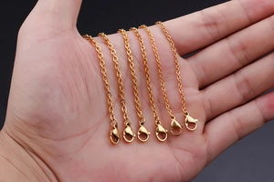 Detail of six thin gold-plated stainless steel chains with lobster clasps on a hand