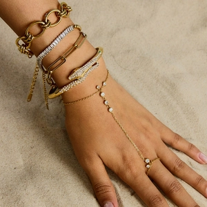 Bracelet serpent élégant en acier titane doré porté par un mannequin sur fond de plage ensoleillé