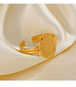 Close-up of golden geometric oval ring with grid texture on elegant cream fabric