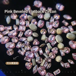 Macro shot of pink cubic zirconia nail charms in mixed shapes on black background