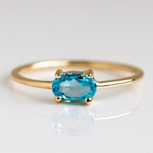 Close-up of gold plated brass ring featuring a vibrant blue oval cut gemstone with reflection