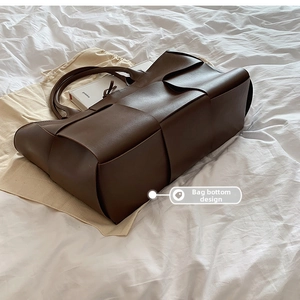 Detailed view of the wide base design of this brown woven faux leather tote bag