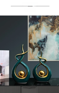 Close-up of modern dark green ceramic abstract sculptures with gold center spheres