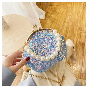 Detail of blue sequin mini handbag featuring a white pearl handle and golden chain strap