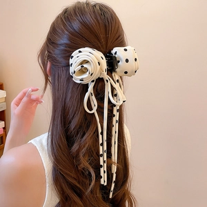 Chiffon polka dot hair claw clip with rose and bow detail on long brown wavy hair