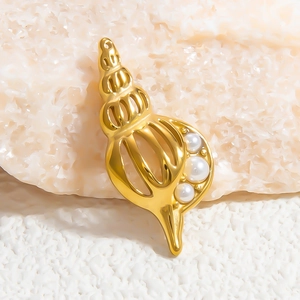 Macro view of a golden conch shell pendant featuring three white inlaid pearls on a rock surface