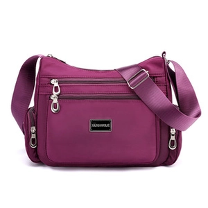 Detail of purple nylon crossbody bag featuring multiple silver zippers and adjustable strap