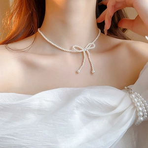 Close-up of pearl bow choker necklace worn by a model with elegant white dress