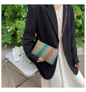 Rainbow rhinestone crossbody bag with gold chain strap shown on model in black suit