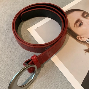 Détail de la ceinture en similicuir rouge à motif crocodile avec boucle ovale argentée
