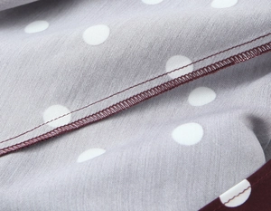 Macro detail of sewing process on grey-purple polka dot dress with precise stitching