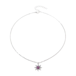 Detailed macro view of silver starburst necklace with purple stone and white diamonds