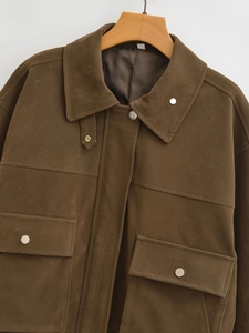 Detail der braunen Wildleder-Fliegerjacke mit Metalldruckknöpfen und Pattentaschen