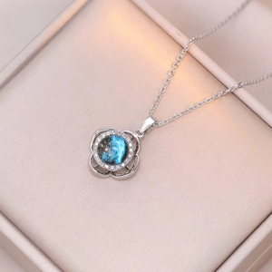 Macro view of rotating flower pendant with starry blue gemstone and silver chain