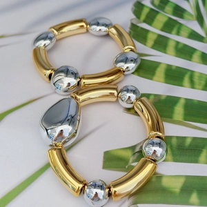 Minimalist elastic bracelet with irregular metallic gold and silver beads on palm leaf