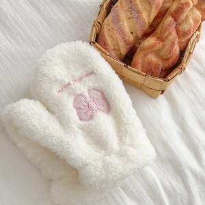 Close-up of white plush mittens with pink bow and beautiful text embroidery details