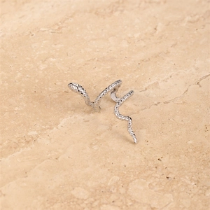 Macro view of a single silver snake ear cuff showing detailed scales and head engraving