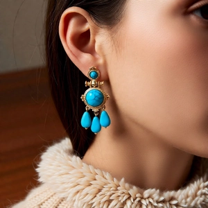 Detail of vintage bohemian round gold earrings with blue turquoise stones on model