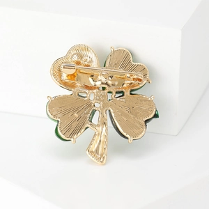 Elegant gold four-leaf clover brooch with green enamel edges and secure pin closure