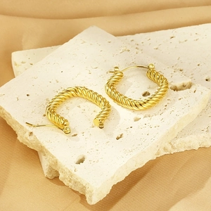Detail of vintage 18K gold plated geometric cable twist earrings on stone texture