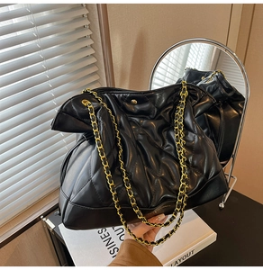 Detail of black quilted chain bag on books with professional indoor lighting
