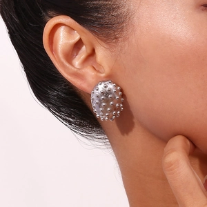 Polished silver stainless steel oval stud earrings with rivet texture on a model