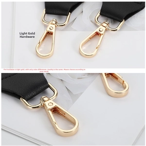 Detailed close-up of light gold swivel lobster clasp and black leather bag strap connector