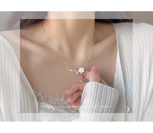 Detailed view of S925 silver flower pendant necklace with tassels on a female model neck