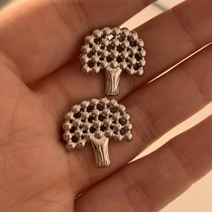 Detail showing the intricate tree-shaped metal earrings with a sleek silver finish