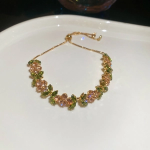 Detail of adjustable gold bracelet with olive green flower zircon and marquise stones