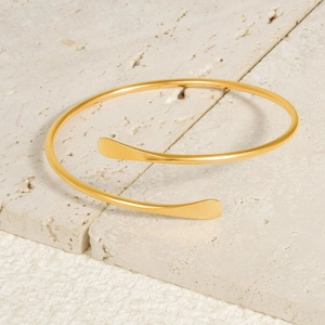 Polished 18k gold 304 stainless steel spiral open bangle on natural stone background