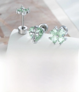Detailed close-up of clover and heart cartilage studs with mint green zircon inlay