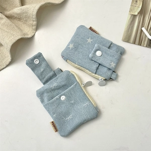 Close-up of denim card holder with white star prints and a bow embroidery detail