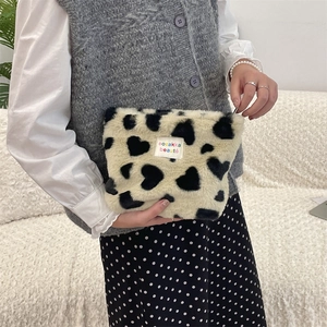 Detail of plush leopard heart pattern makeup bag with colorful logo label on soft fabric