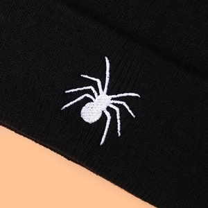 Close-up detail of high-quality white spider embroidery on a black knitted winter beanie