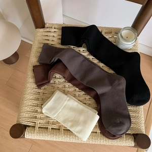 Cozy combed cotton calf socks in multiple neutral colors on a woven stool for fall style