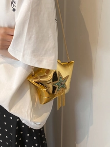 Detail of star-shaped acrylic bag with gold mirror finish and green rhinestone tassel decoration