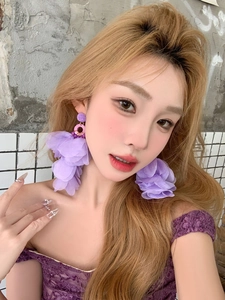 Gros plan détaillé d'une longue boucle d'oreille à pampille fleurie violette sur un mannequin