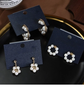 Detailed set of three freshwater pearl gold-plated earrings on elegant navy jewelry cards