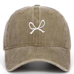 Detail of white embroidered bow design on brown washed cotton baseball cap texture