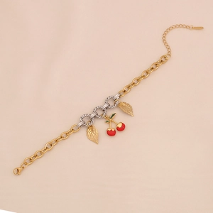 Detail view of gold chain bracelet with red enamel cherry charms and gold leaf pendants