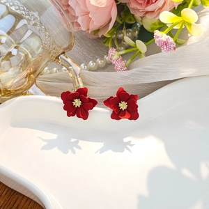 Macro shot of red floral earrings with golden pistils on an elegant ceramic plate