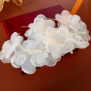 Détail de créoles fleurs en maille blanche avec touches dorées et perles de cristal