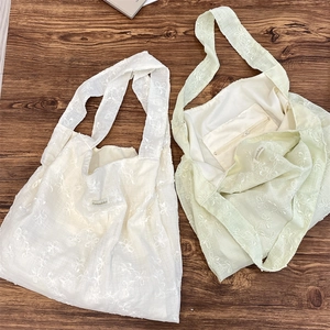 Detail view of floral embroidery tote bags showing the inner zipper pocket and brand tag